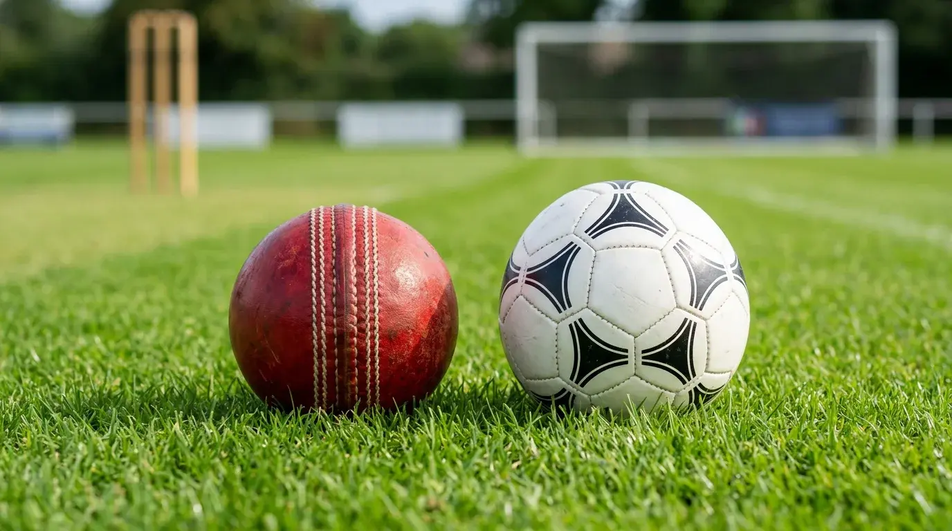 Pelota de cricket y balon de futbol uno al lado del otro sobre un campo deportivo